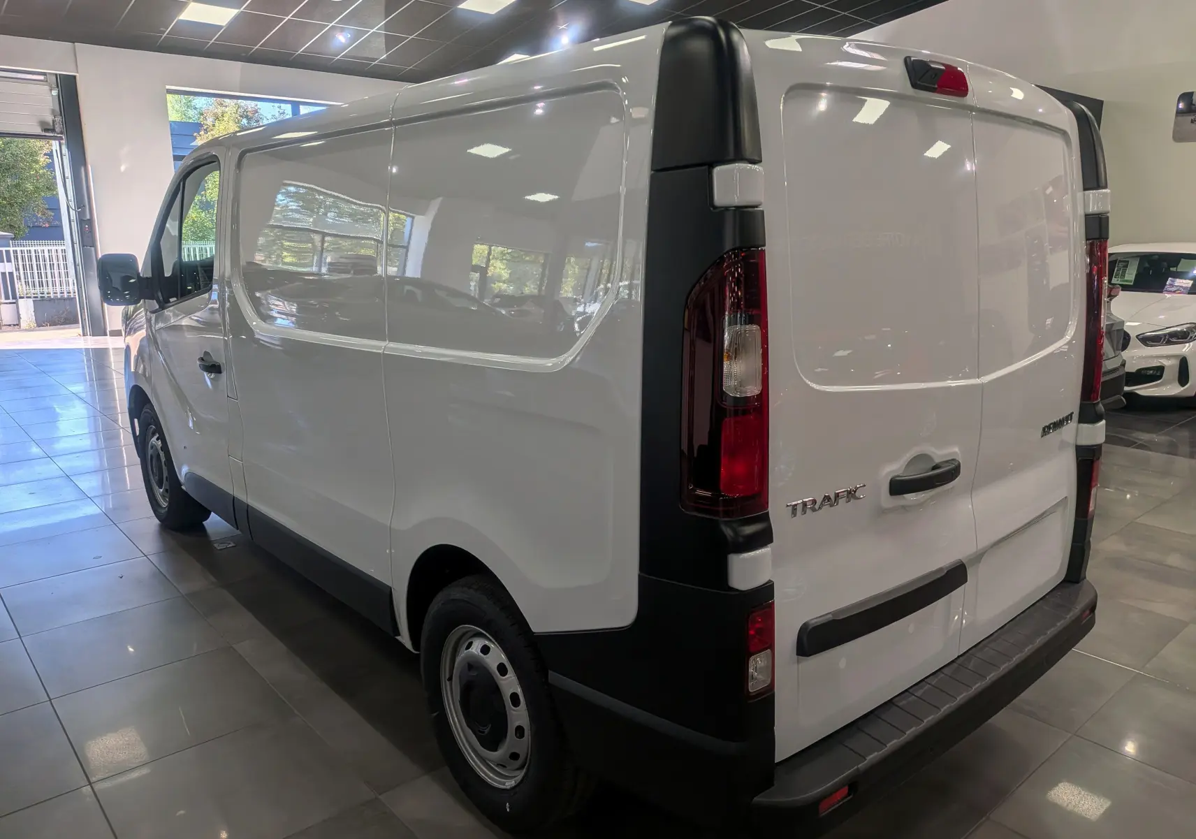 Renault Trafic Fourgon blanc glacier vu de trois quarts arrière droit, avec portes arrière fermées et feux rouges.