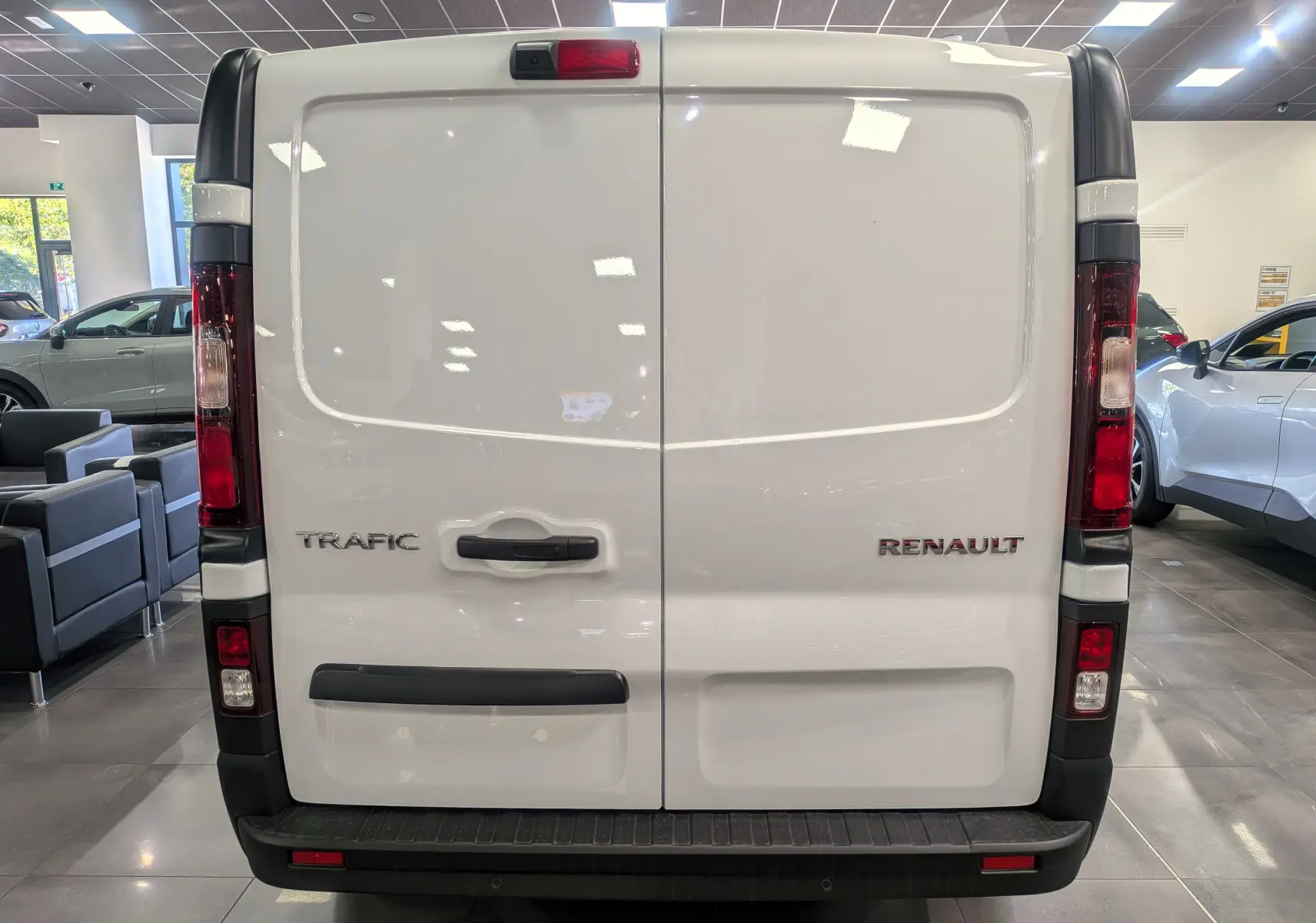 Vue arrière du Renault Trafic Fourgon blanc glacier avec portes battantes et feux verticaux rouges.
