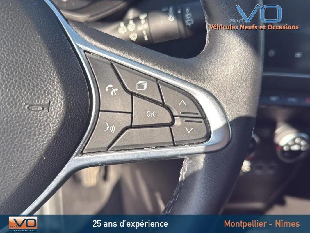 Gros plan sur les commandes multifonctions du volant noir du Renault Clio gris 2022, avec boutons de réglage et appel.