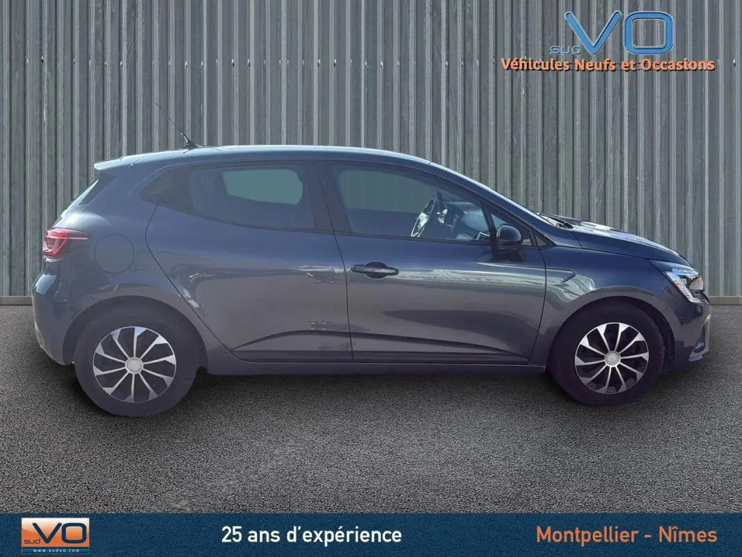 Profil côté gauche d'une Renault Clio gris 2022 V TCe 90 Equilibre garée devant un mur métallique.