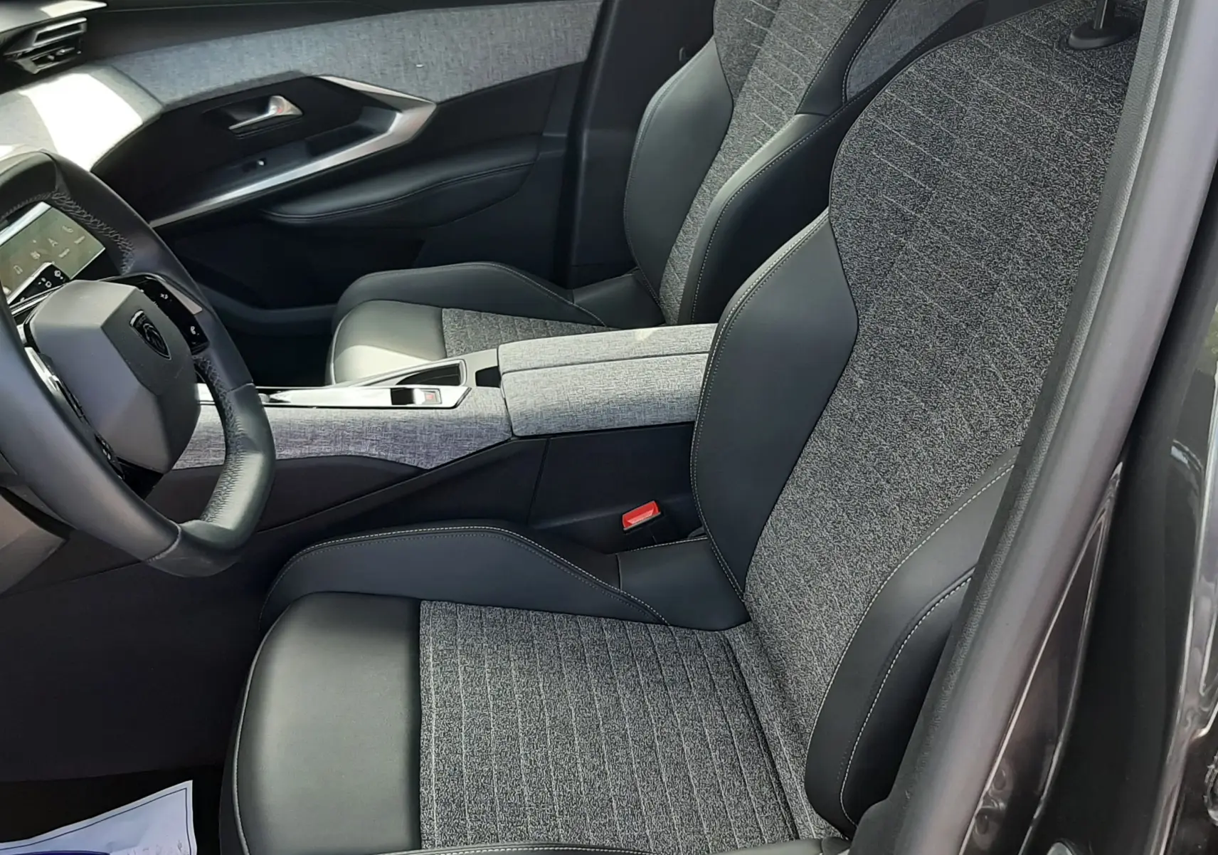 Vue intérieure côté conducteur du Peugeot 5008 Hybrid 145ch Allure 2025, sièges tissu gris et cuir noir, détails modernes.