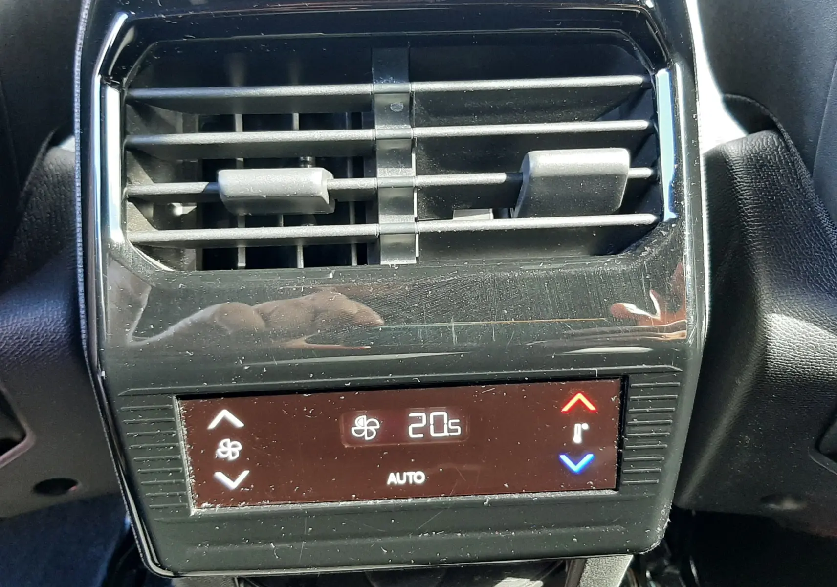 Vue rapprochée de la sortie d’air arrière et du panneau de contrôle de la climatisation digitale du Peugeot 5008 gris titane.