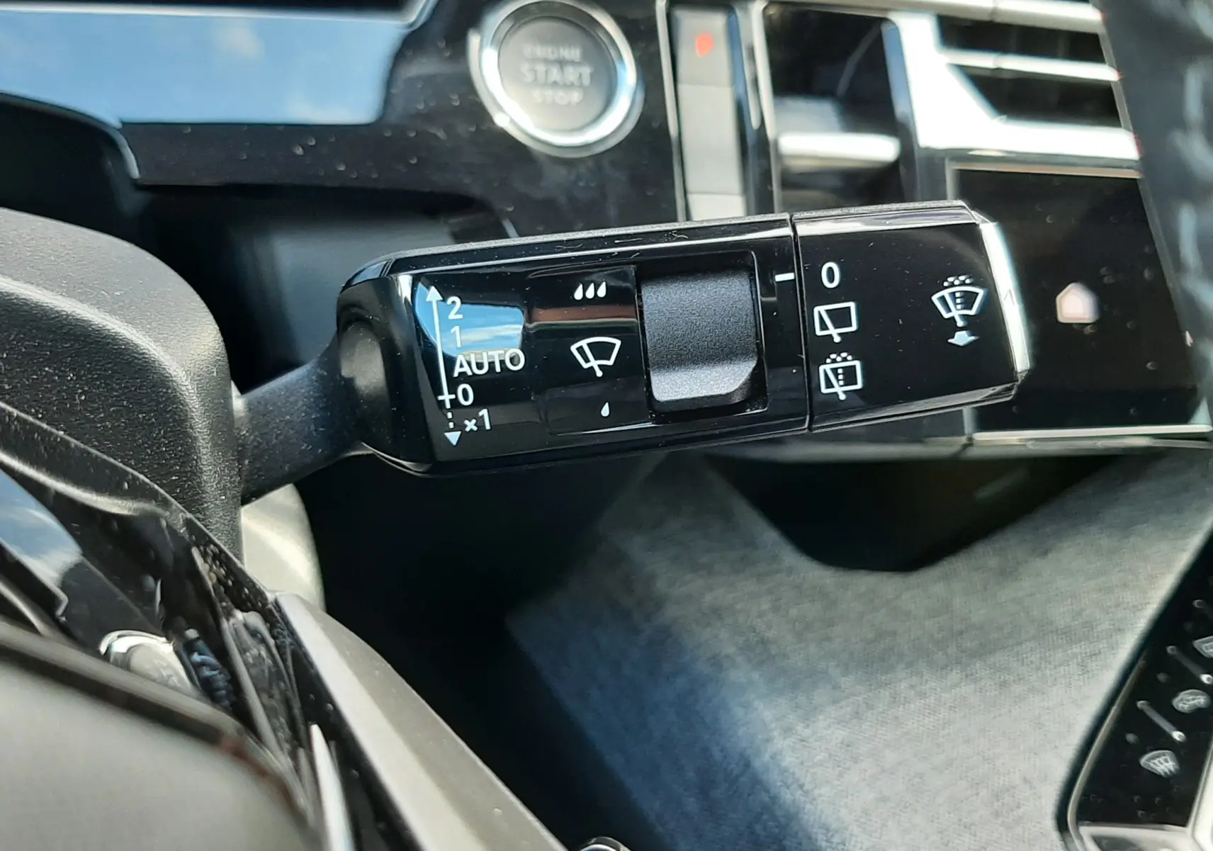 Gros plan sur la commande des essuie-glaces à droite du volant dans l’habitacle gris noir du Peugeot 5008 Hybrid 2025.