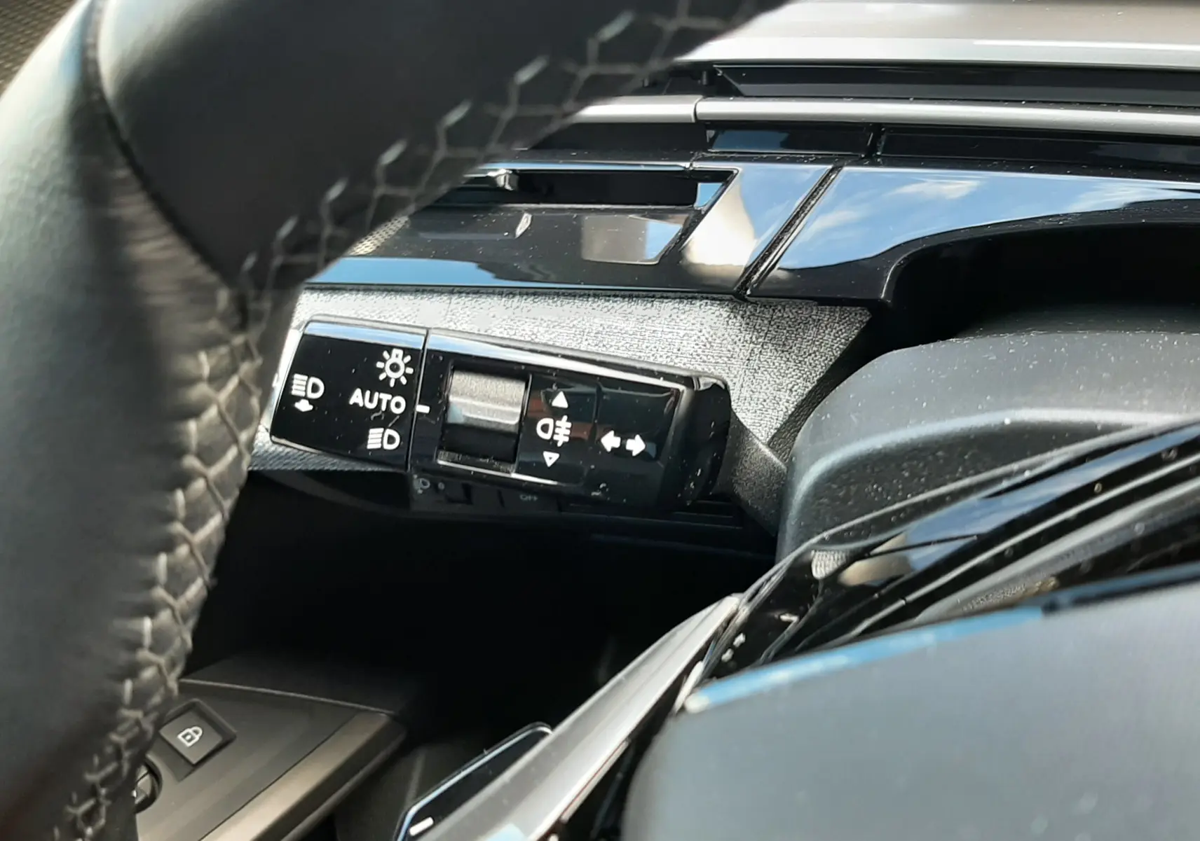 Gros plan sur la commande des feux et clignotants à gauche du volant dans l’habitacle gris noir du Peugeot 5008 Hybrid 2025.
