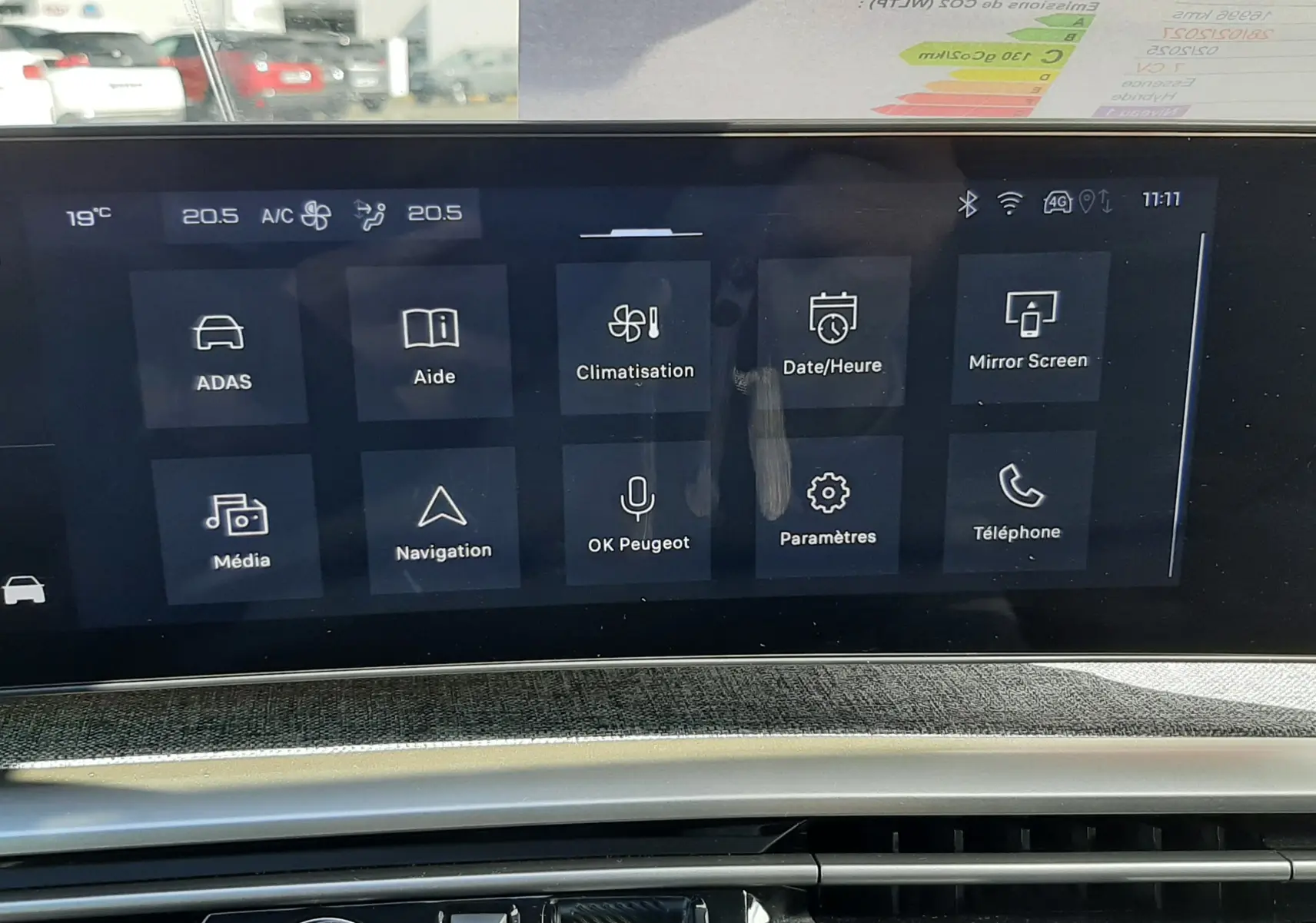 Vue rapprochée de l’écran tactile central et de la console de la Peugeot 5008 Hybrid 145ch Allure gris titane, affichant les menus climatisation et navigation.