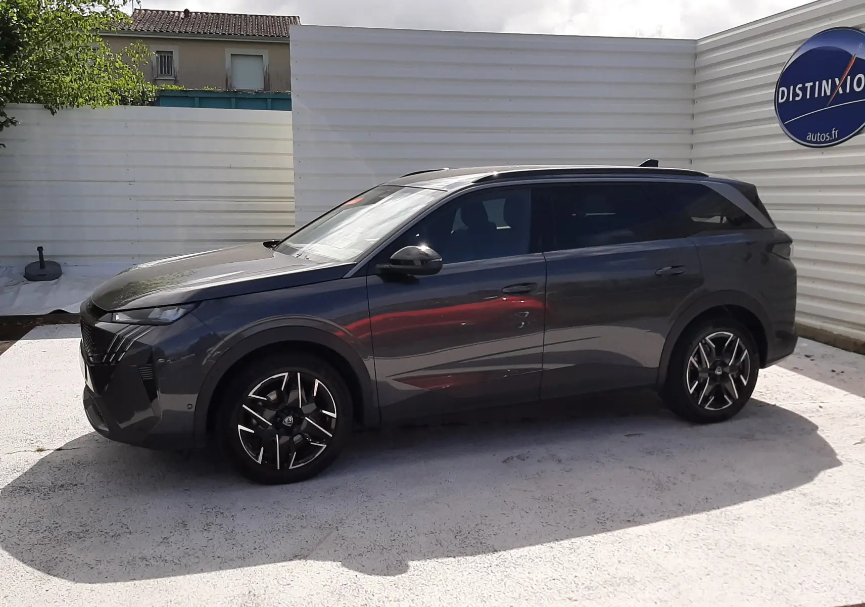 Peugeot 5008 Hybrid gris titane métal vue de profil côté gauche, avec jantes alliage noires et toit panoramique.