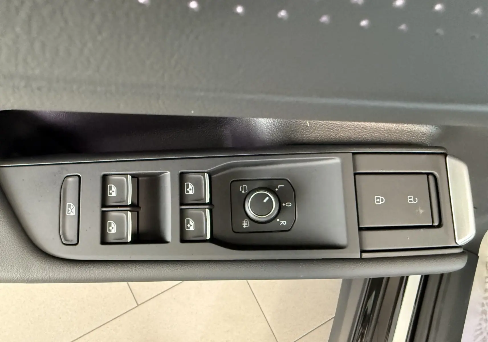 Vue rapprochée des commandes de lève-vitres et rétroviseurs sur la porte côté gauche d’un Volkswagen T-Roc noir intense.
