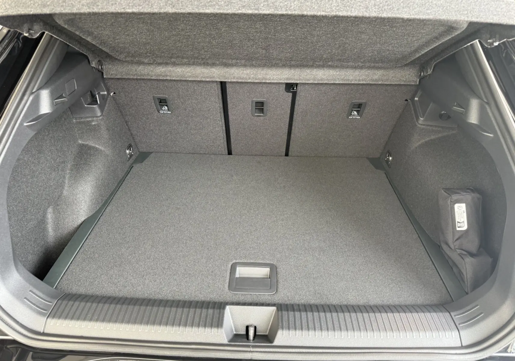 Coffre ouvert vu de l'arrière d'un Volkswagen T-Roc R-Line noir intense, montrant un espace de chargement propre et bien fini.