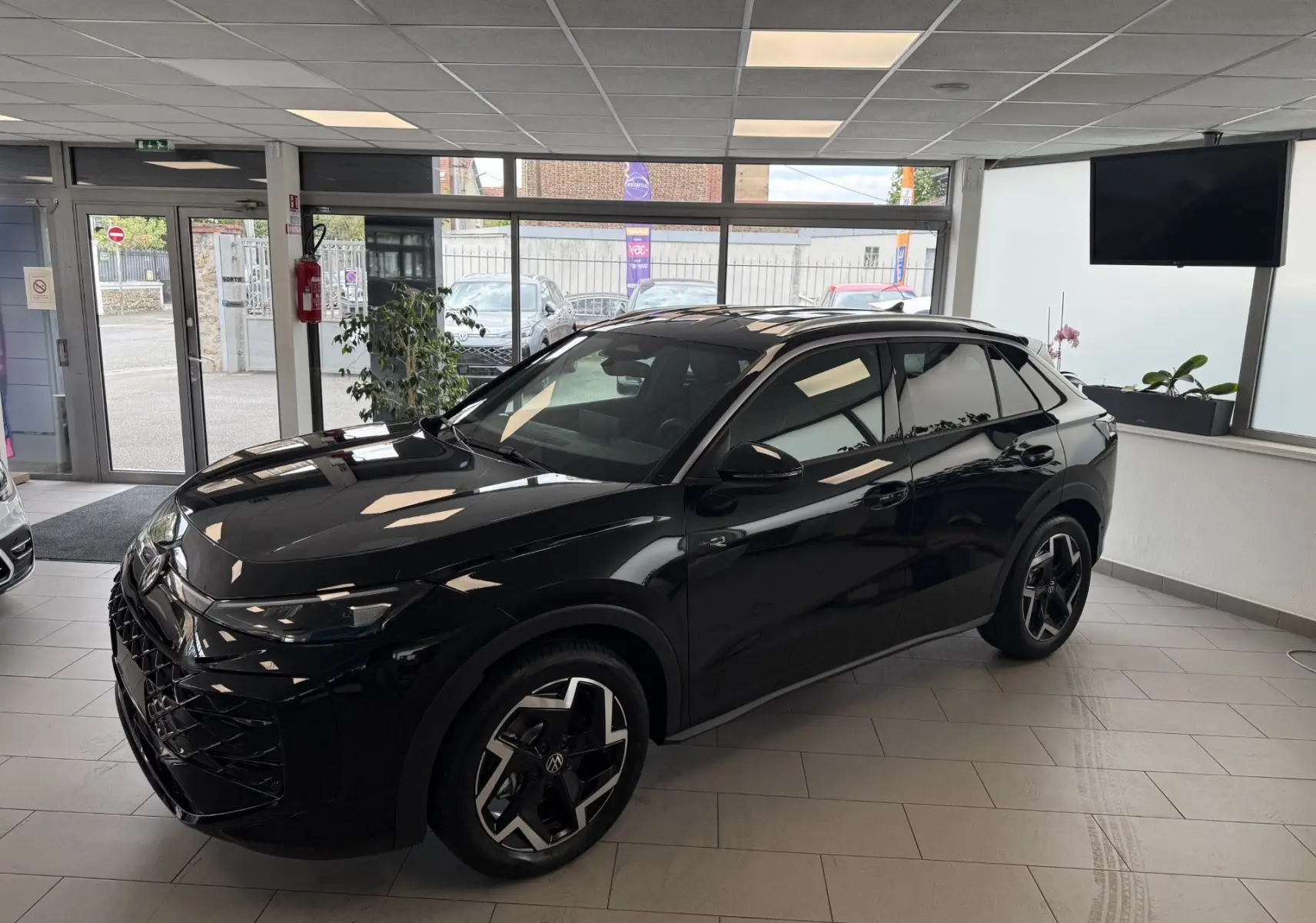 Volkswagen T-Roc R-Line eTSI 150Ch noir intense, vue 3/4 avant droit en intérieur lumineux.