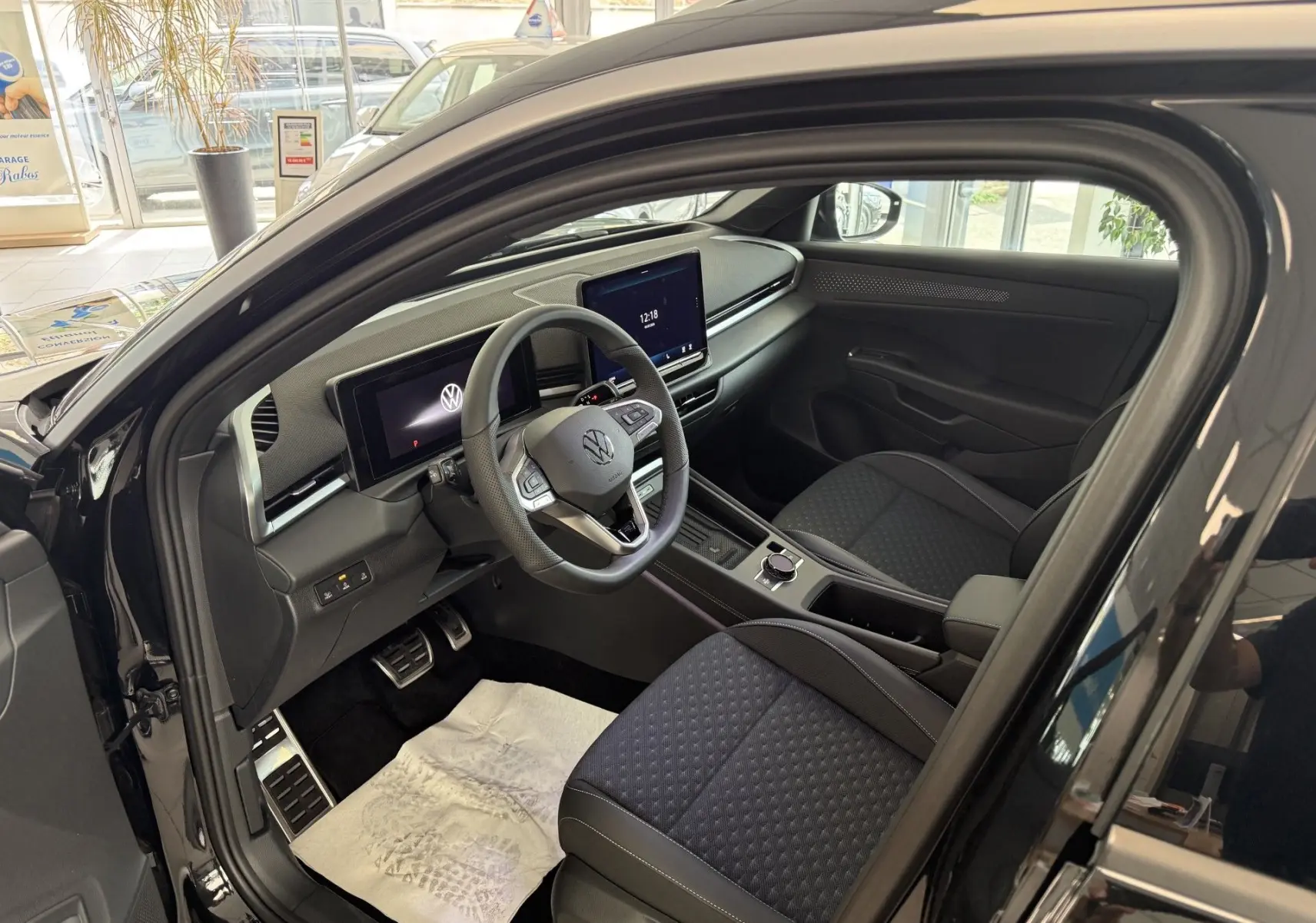 Vue intérieure côté conducteur du Volkswagen T-Roc R-Line noir intense 2026, avec tableau de bord digital et sièges tissu noir.