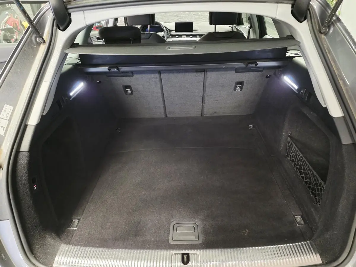 Coffre spacieux ouvert de l'Audi A4 Avant gris 2018, avec éclairage intérieur et filet de rangement latéral.