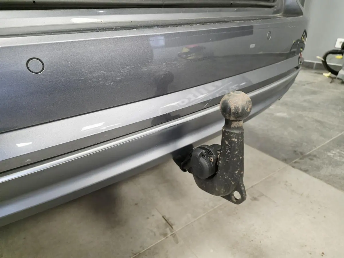 Gros plan sur le crochet d'attelage noir fixé au pare-chocs arrière gris métallisé d'une Audi A4 Avant 2018.