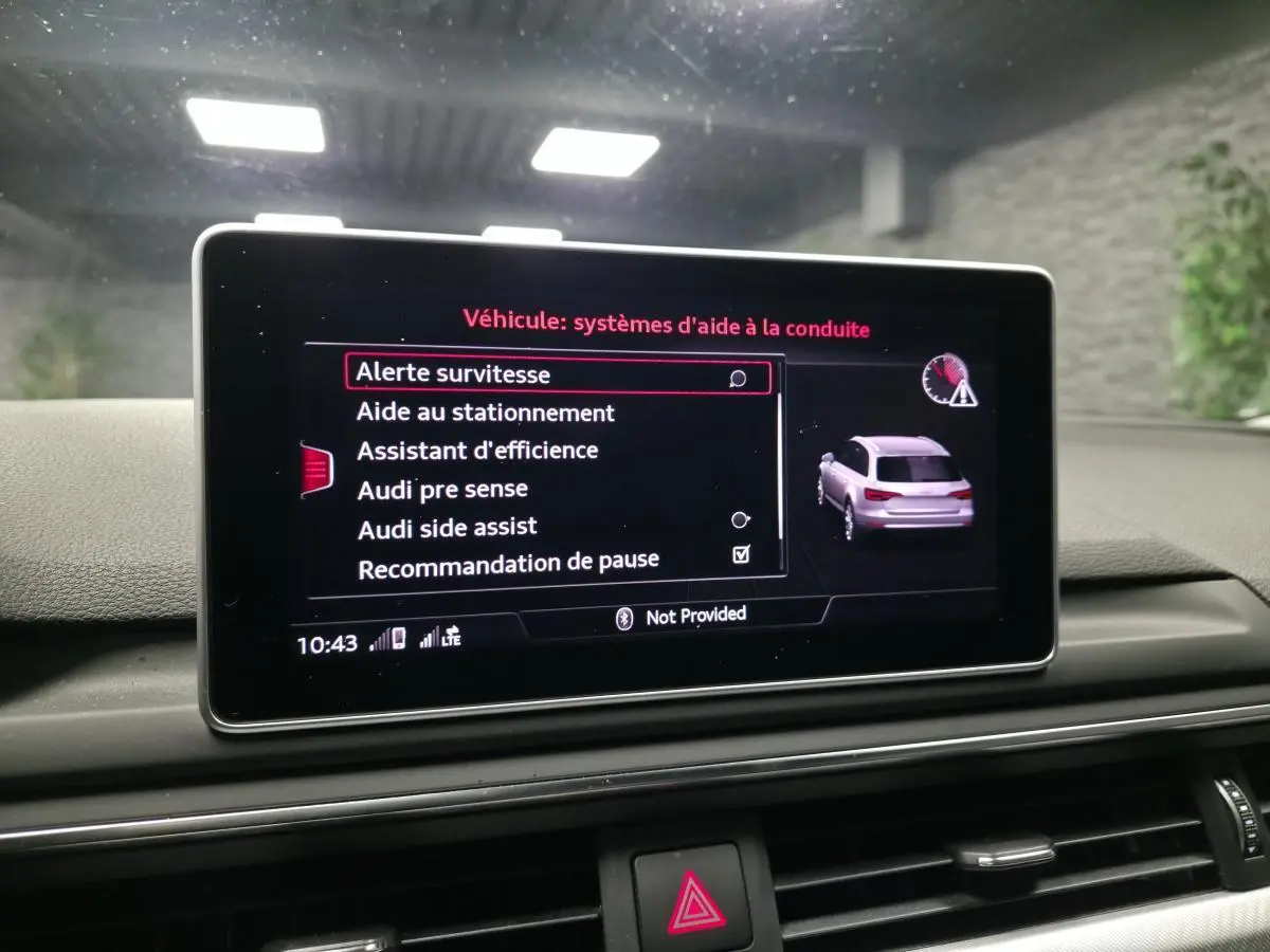 Écran central de l'Audi A4 gris 2018 affichant les options d'aide à la conduite avec vue arrière du véhicule en miniature.
