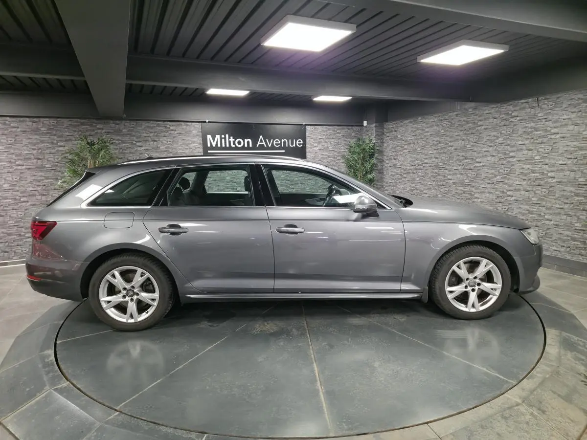 Audi A4 Avant gris métallisé vue de profil côté gauche, jantes alu 17 pouces et intérieur visible en arrière-plan.