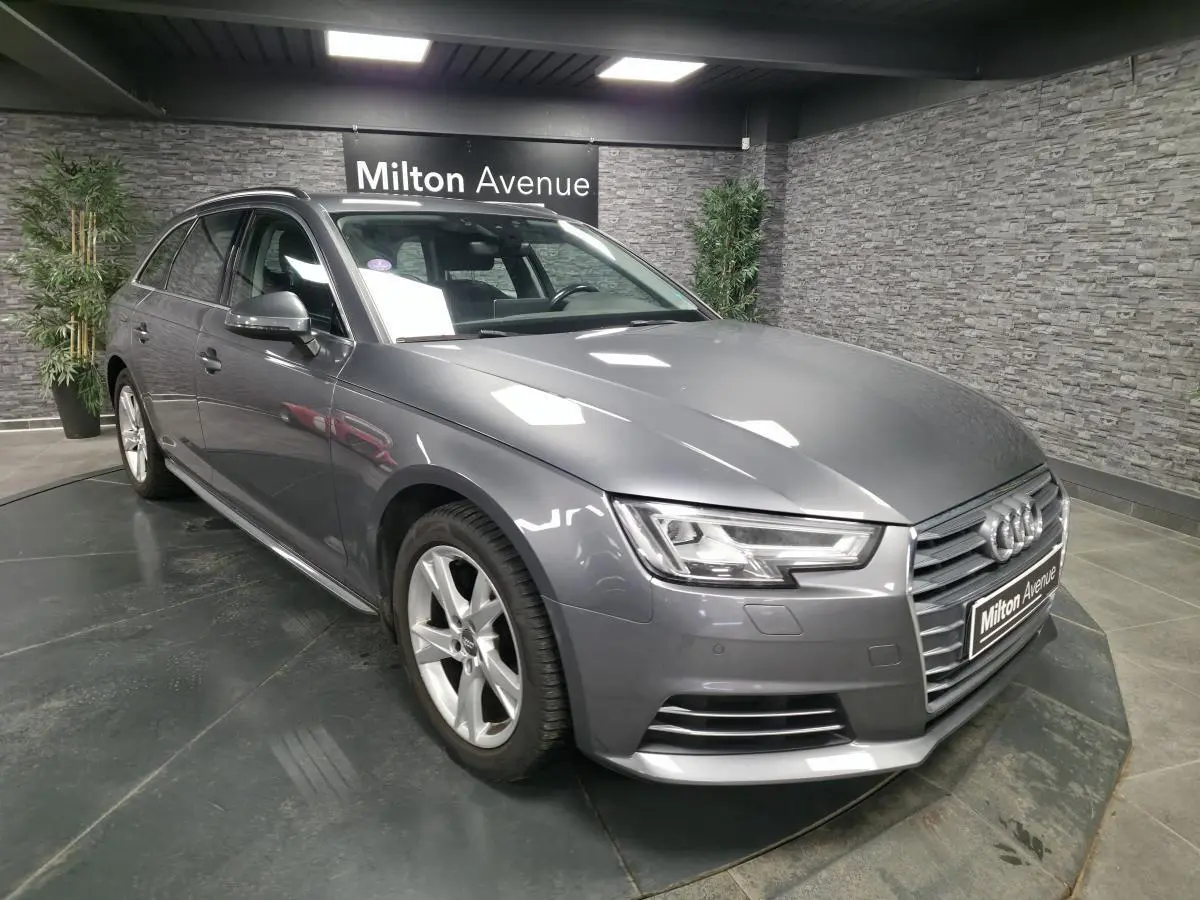 Audi A4 Avant gris métallisé vue 3/4 avant droit avec jantes alu 17 pouces dans un showroom intérieur.