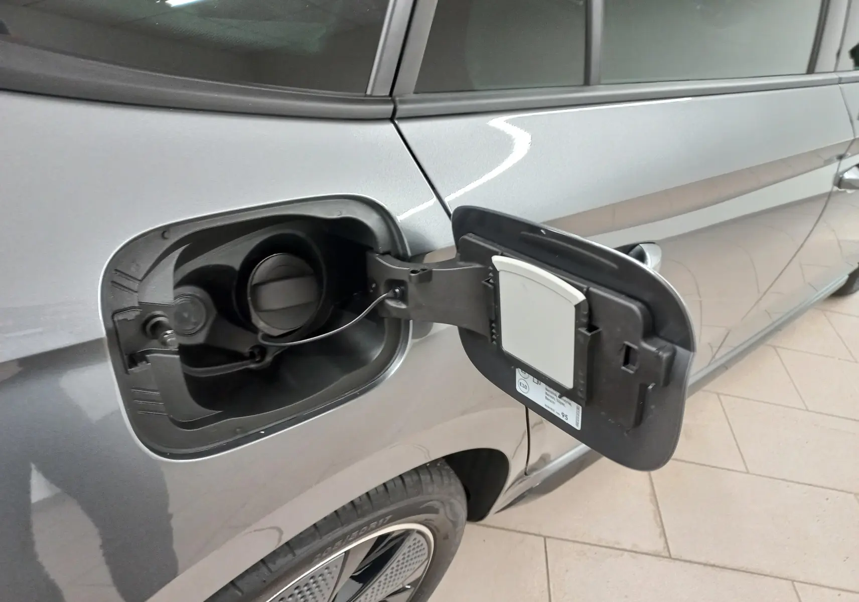 Gros plan sur la trappe à carburant ouverte côté gauche d'une Skoda Scala 2025 gris graphite métallisé.