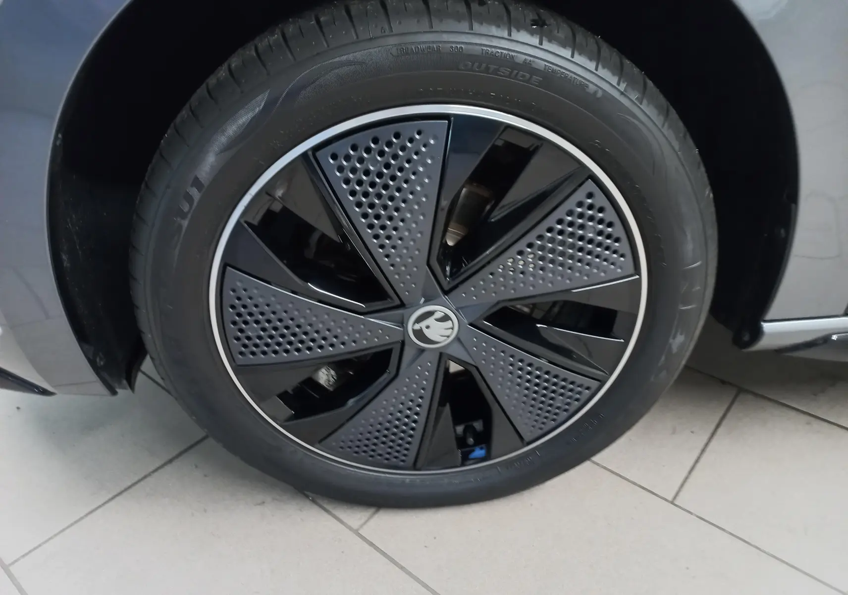 Gros plan sur la roue avant droite de la Skoda Scala 1.5 TSI 150 DSG7 Monte-Carlo gris graphite avec jante noire au design perforé.