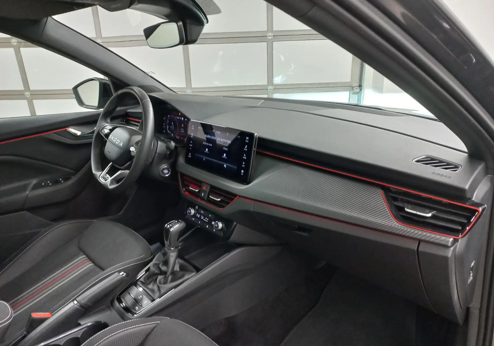 Intérieur côté conducteur d'une Skoda Scala Monte-Carlo 2025 avec tableau de bord noir et détails rouges.