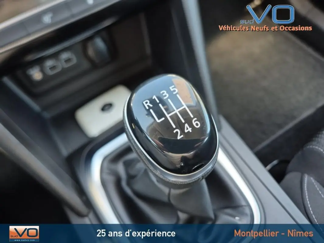 Gros plan sur le levier de vitesses manuel noir de la Renault Mégane IV Business gris, intérieur avec console centrale visible.