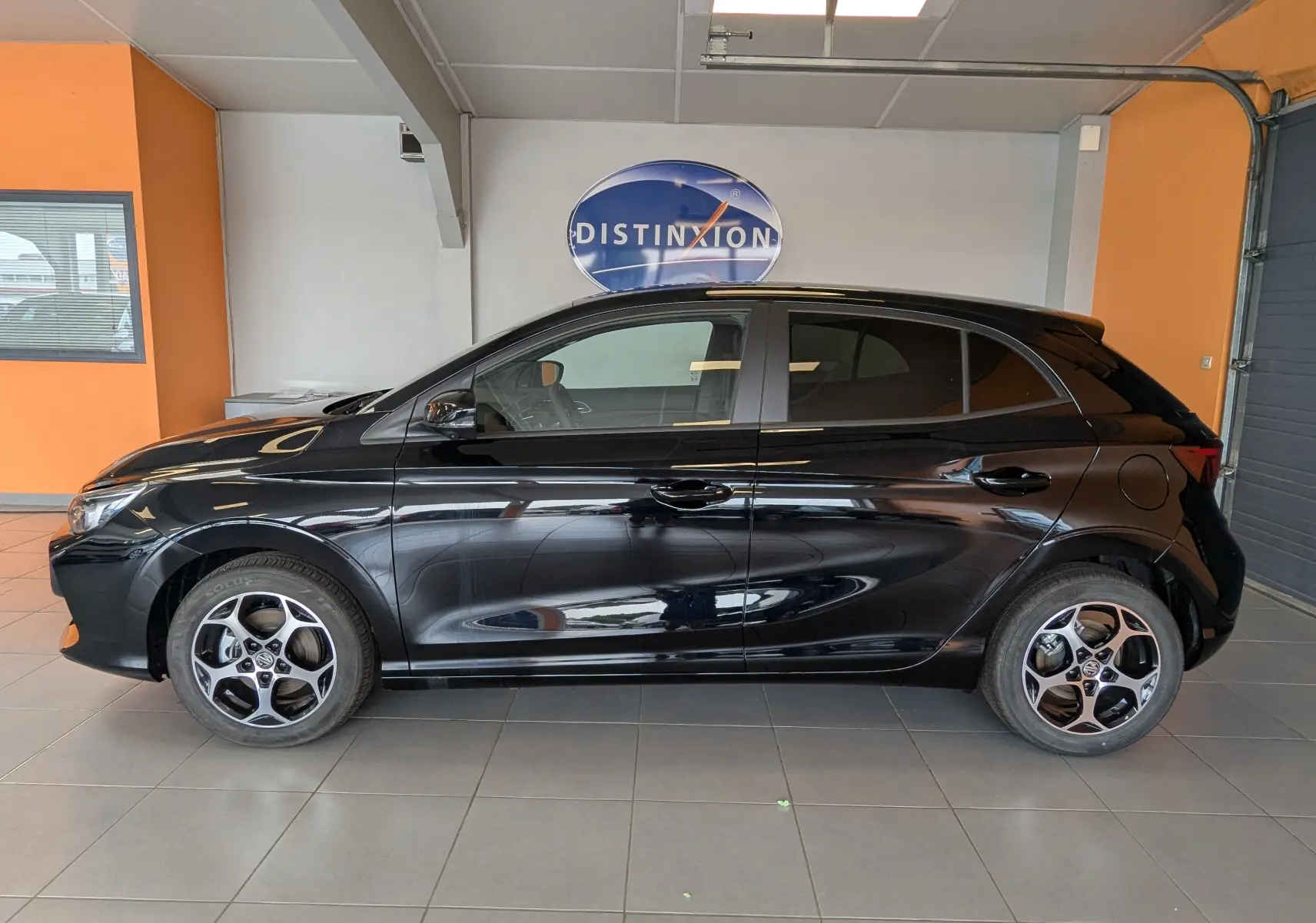 Vue de profil côté gauche d’une MG3 1,5 HYBRID+ 195cv Luxury noire Pebble Black avec jantes bi-ton en showroom.