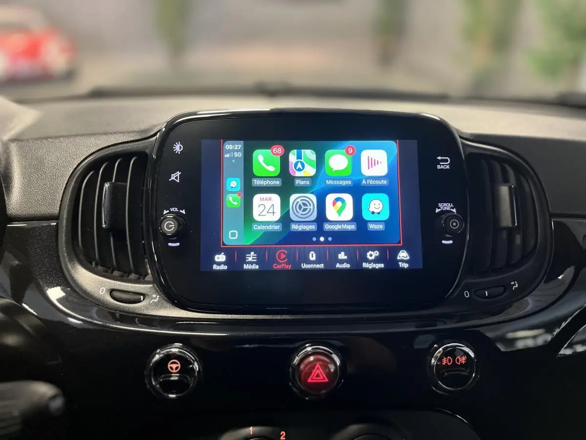 Écran tactile central allumé avec interface Apple CarPlay sur tableau de bord noir brillant d'une Fiat 500 Dolcevita 2023.