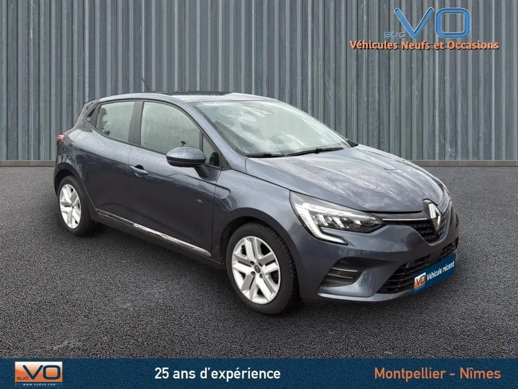 Renault Clio V Blue dCi 85 Business gris foncé vue 3/4 avant droit sur sol noir devant un mur métallique.