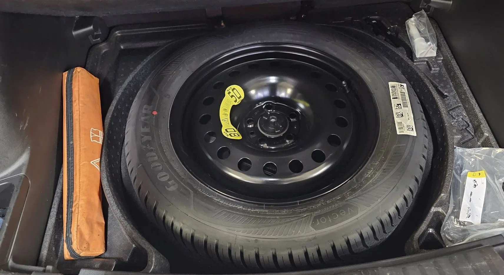 Roue de secours noire Goodyear dans le coffre d'un Jeep Compass 2023, avec trousse à outils orange à gauche.