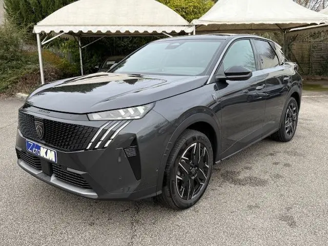 Peugeot 3008 Hybrid 145 GT gris titane en 3/4 avant droit, avec jantes alliage bicolores et calandre noire distinctive.