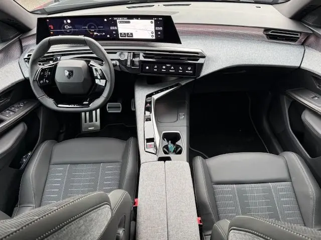 Vue intérieure avant du Peugeot 3008 Hybrid 145 GT avec volant cuir multifonction, sellerie tissus Uziris et écran panoramique incurvé.