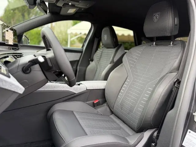 Vue intérieure côté conducteur du Peugeot 3008 Hybrid 145 GT avec sellerie tissus Uziris gris et volant cuir multifonction.