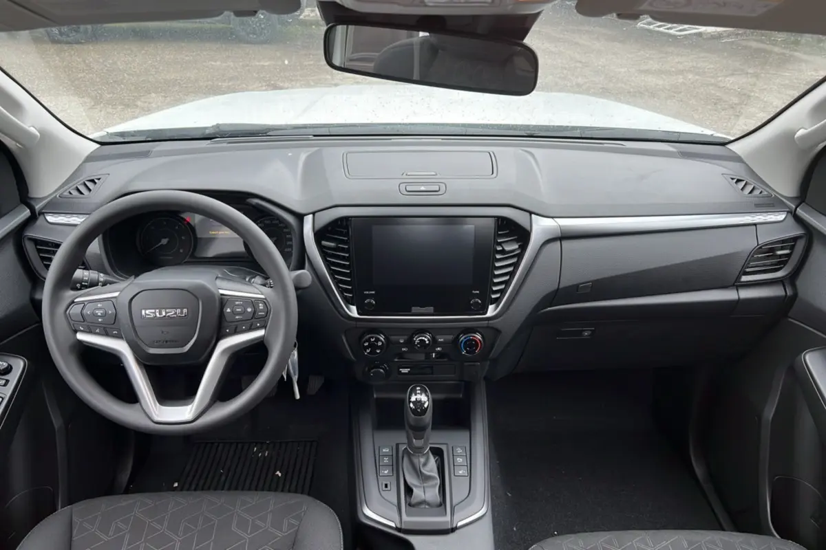 Vue intérieure frontale de l'Isuzu D-MAX 2026 Splash White avec tableau de bord moderne et volant multifonctions.