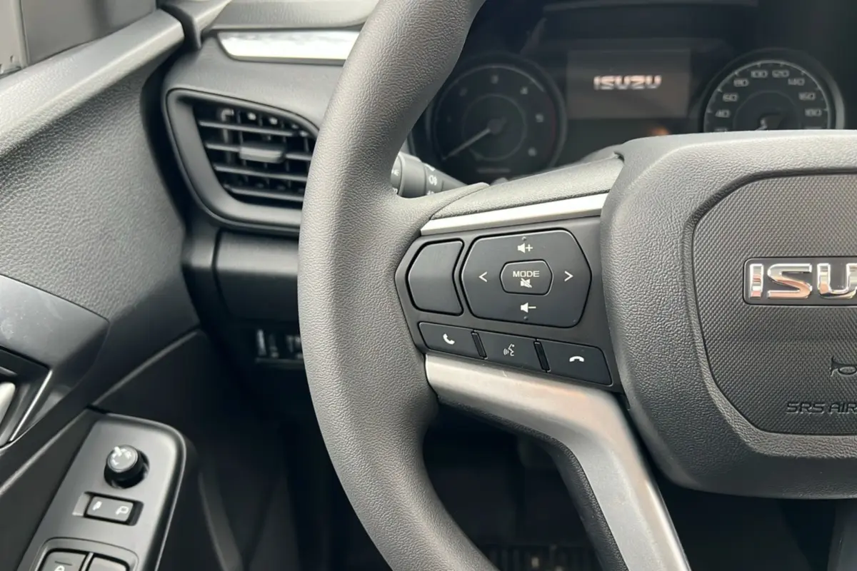 Vue rapprochée du volant multifonctions gris foncé de l'Isuzu D-MAX 2026 avec commandes audio et téléphone intégrées.