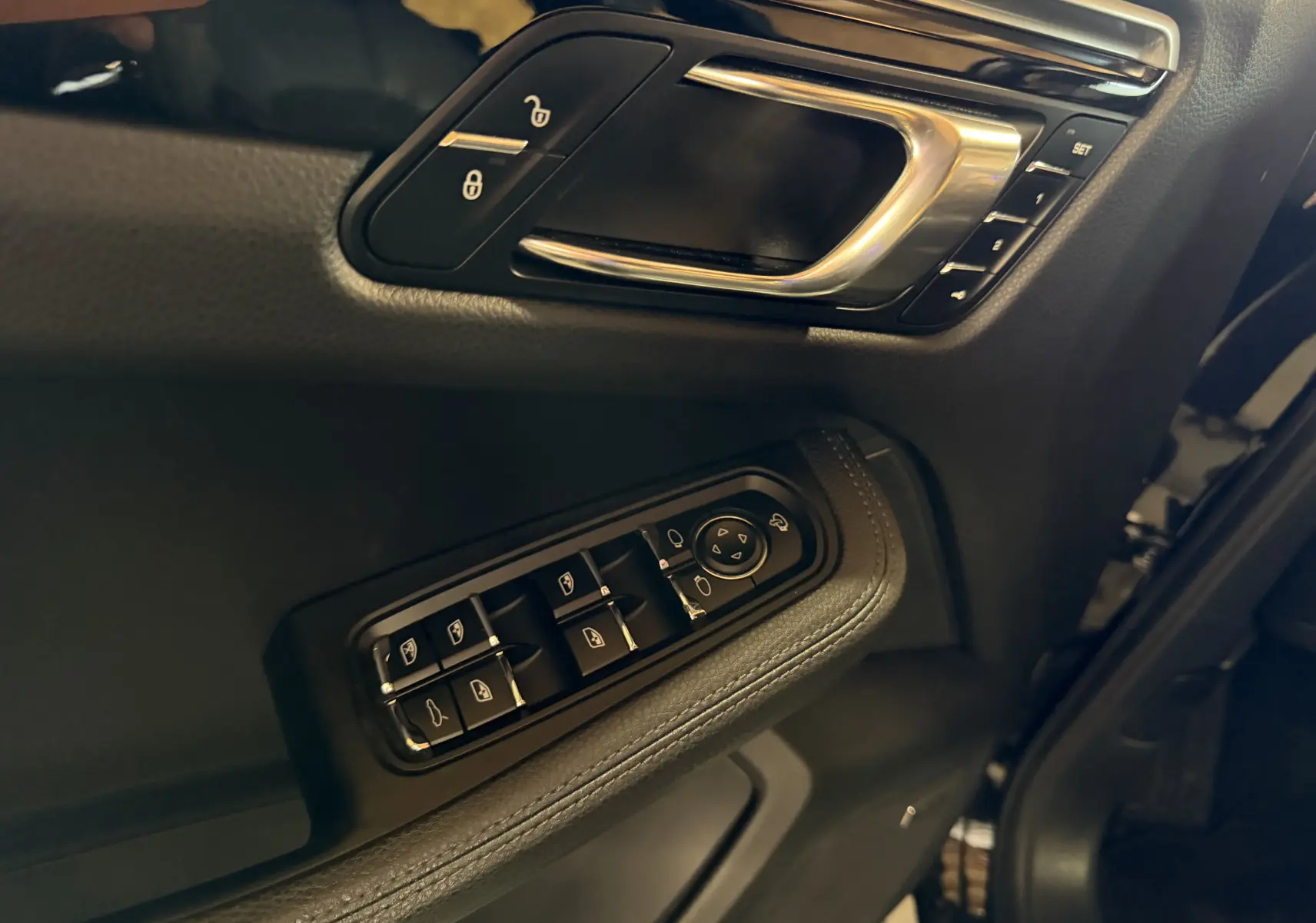 Détail de la porte côté conducteur du Porsche Macan S noir, avec commandes électriques des vitres et poignée alu.
