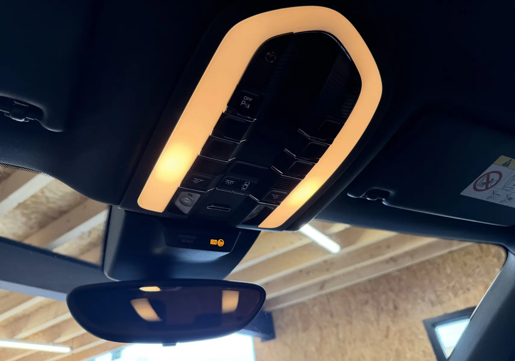 Vue intérieure du plafonnier allumé au-dessus du rétroviseur dans un Porsche Macan S noir, avec commandes intégrées.