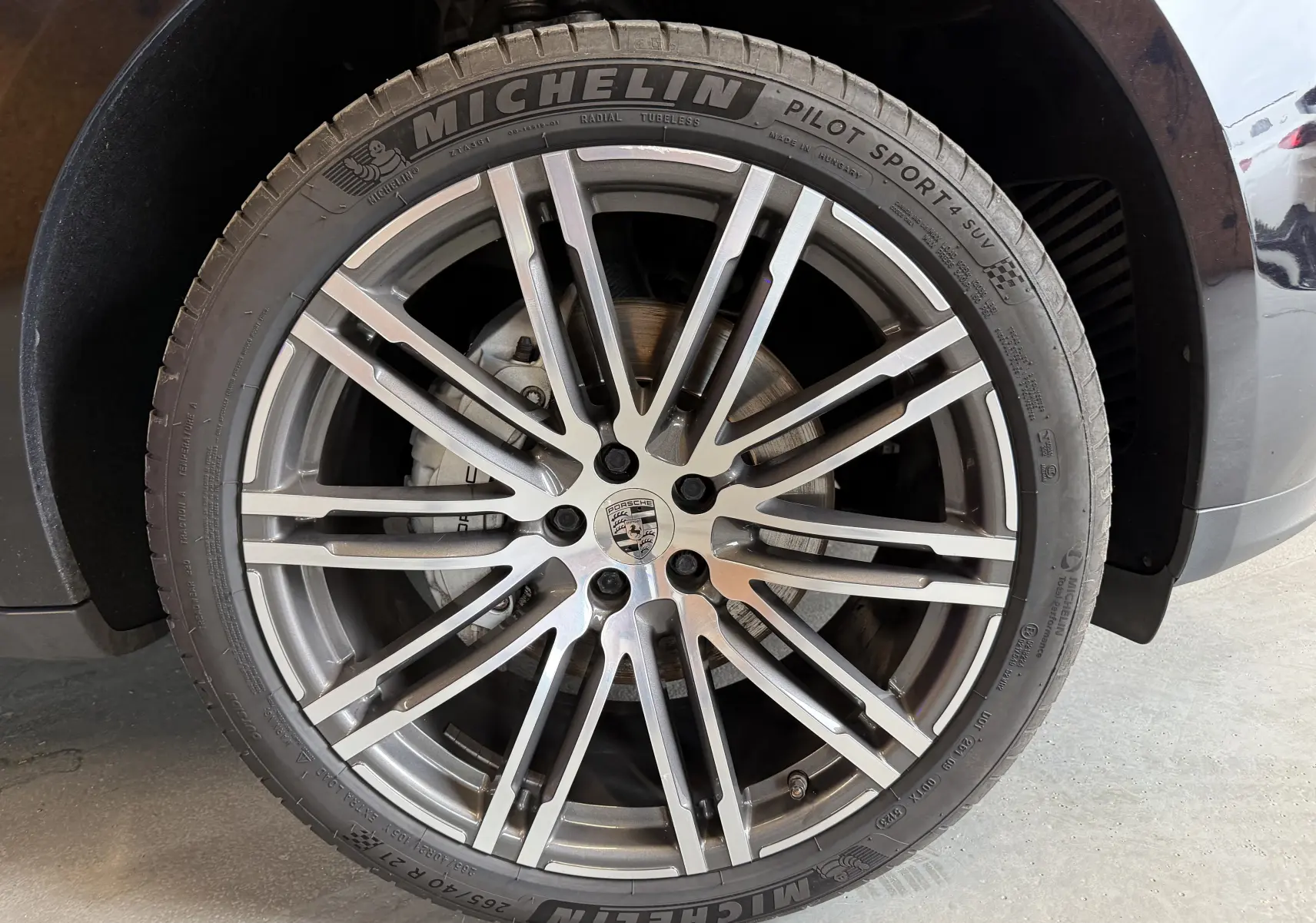 Gros plan sur la jante alu 21 pouces et pneu Michelin d’un Porsche Macan S 3.0i noir, avec logo Porsche visible au centre.