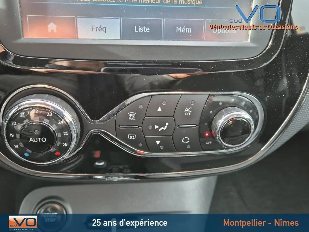 Gros plan sur la console centrale du Renault Captur gris 2014, mettant en valeur les commandes de climatisation automatique et l'écran tactile.