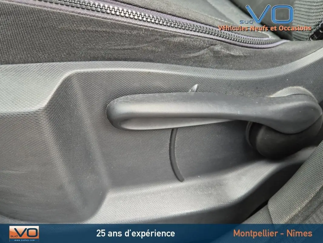 Poignée de réglage manuelle de siège en plastique noir à l'intérieur d'un Renault Captur gris, version 2014.