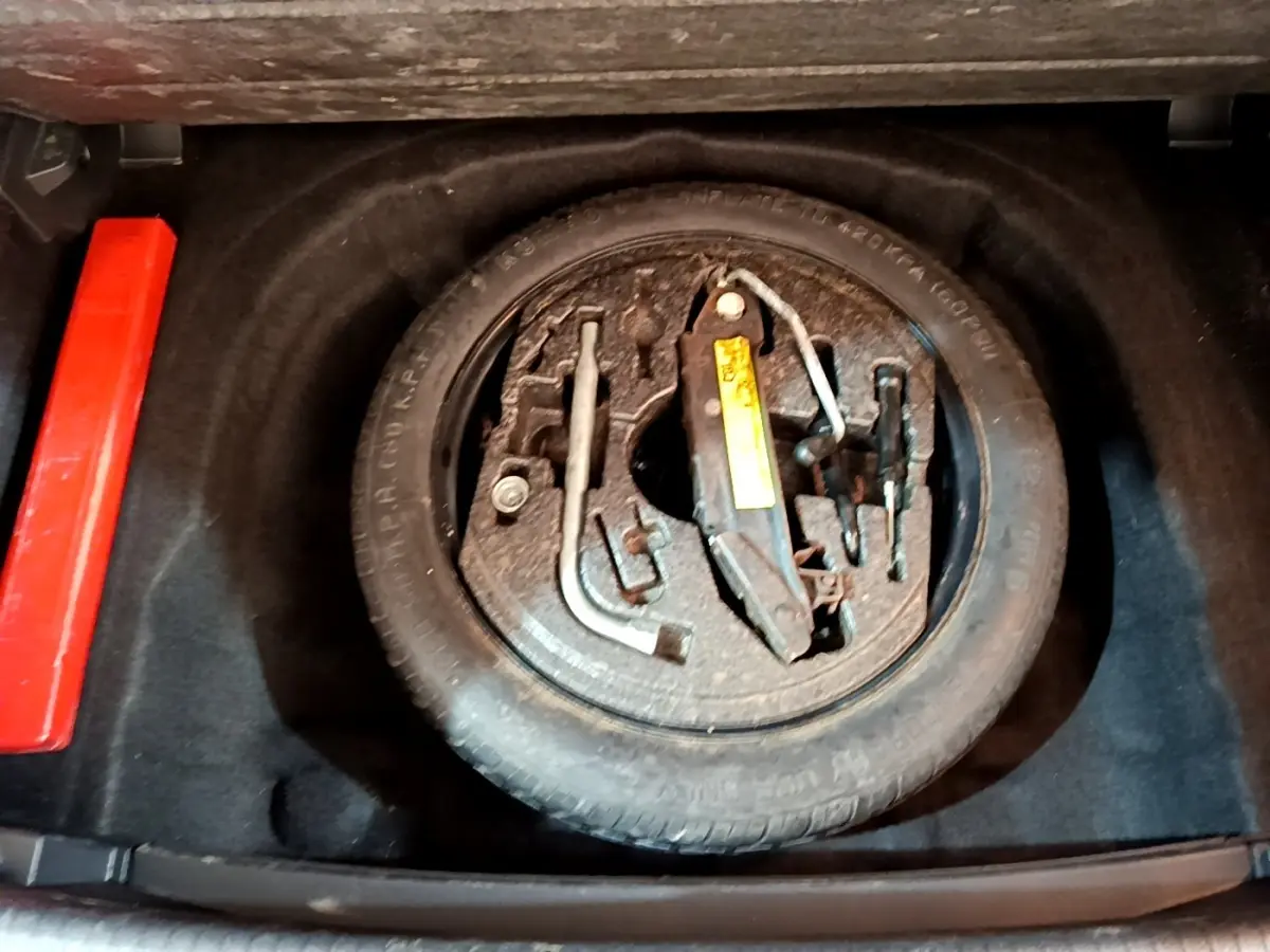 Vue plongeante sur la roue de secours et les outils de bord dans le coffre d'une Volkswagen Golf gris clair 2017