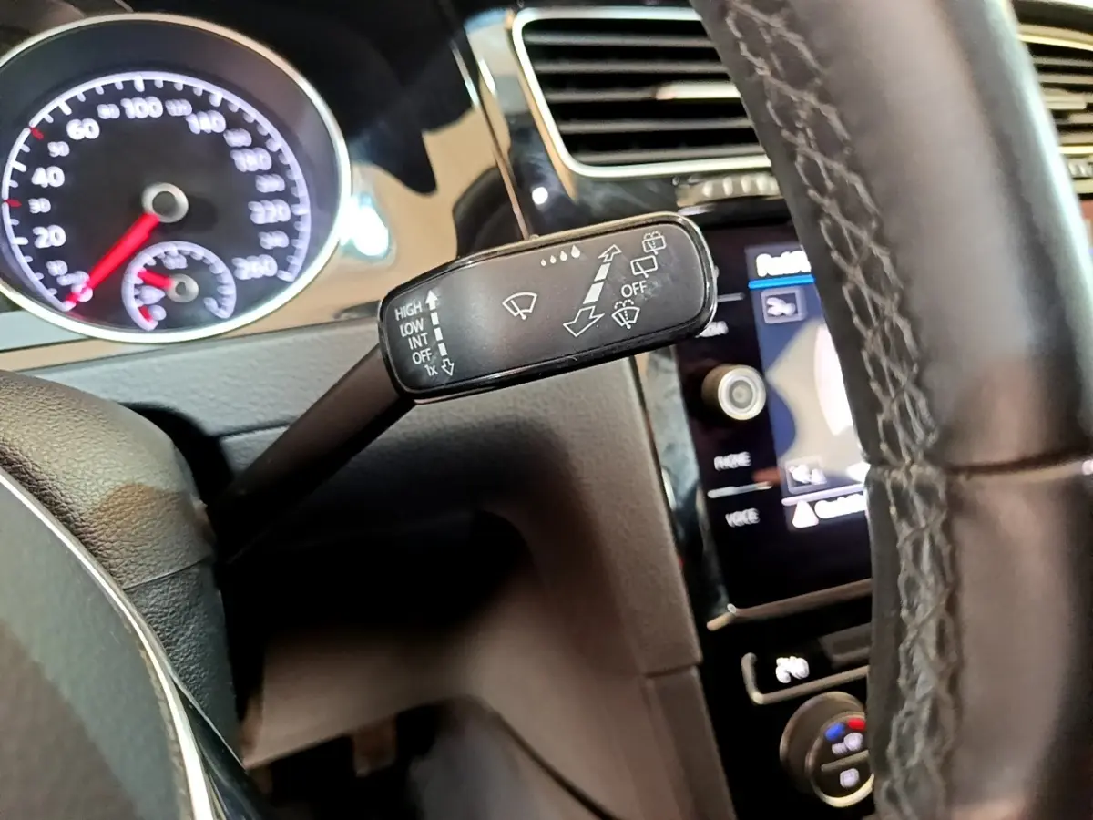 Gros plan sur la manette d’essuie-glace à gauche du volant cuir d’une Volkswagen Golf gris clair 2017.