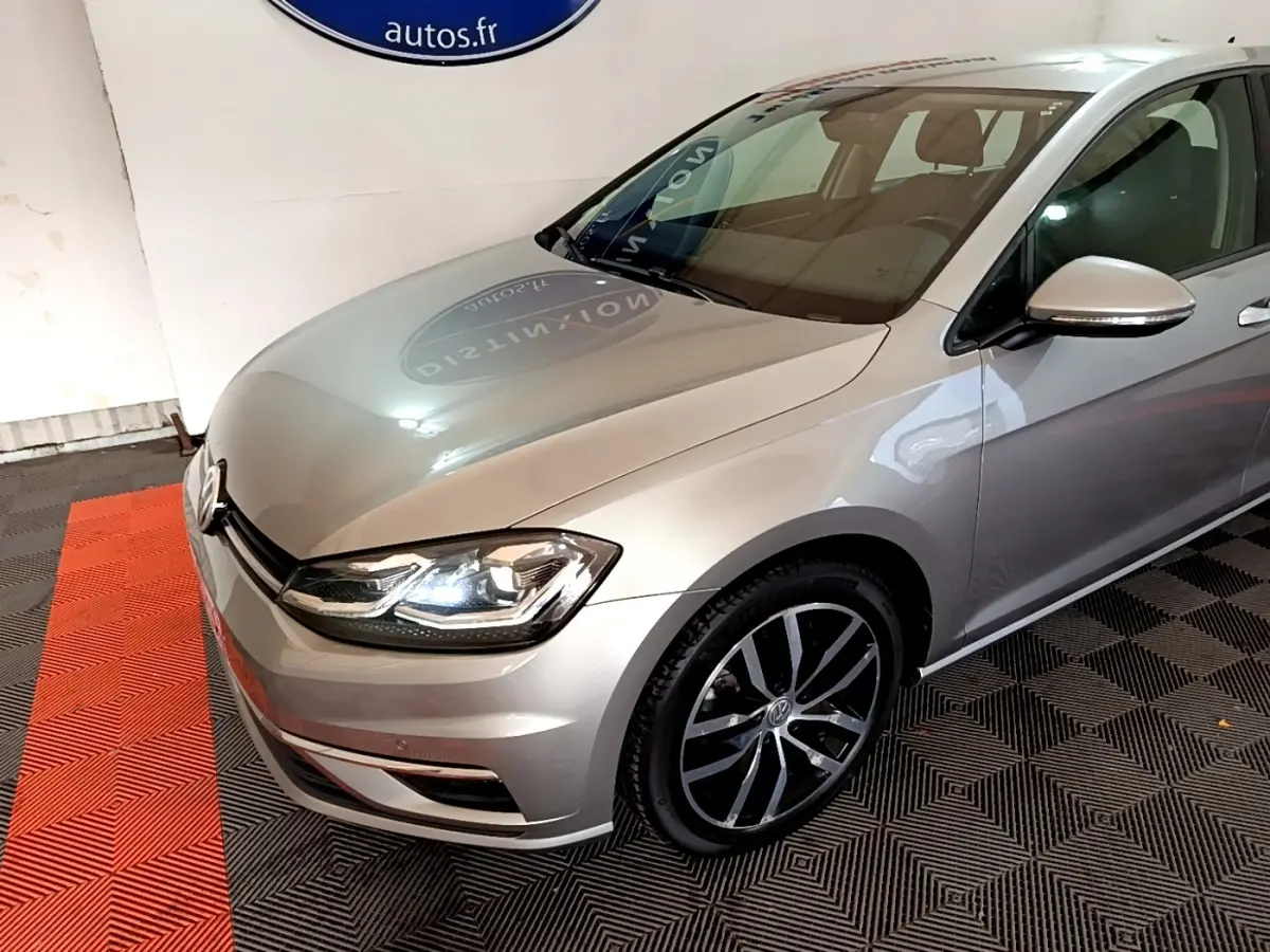 Vue 3/4 avant droit d'une Volkswagen Golf gris clair avec phares LED et jantes alliage distinctives.