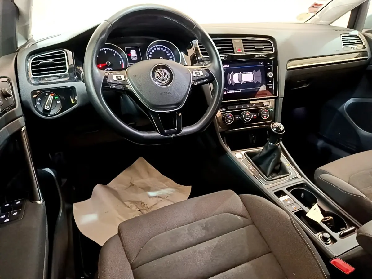 Intérieur de Volkswagen Golf 2017 vu côté conducteur, volant cuir, tableau de bord avec écran tactile et boîte manuelle.