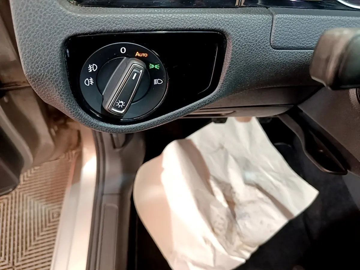 Gros plan sur la commande d’éclairage côté gauche du tableau de bord d’une Volkswagen Golf gris clair de 2017.