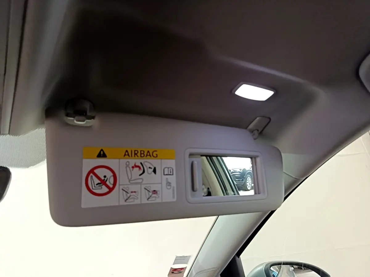 Miroir de pare-soleil côté conducteur dans un Volkswagen Golf gris clair, intérieur clair visible en reflet.