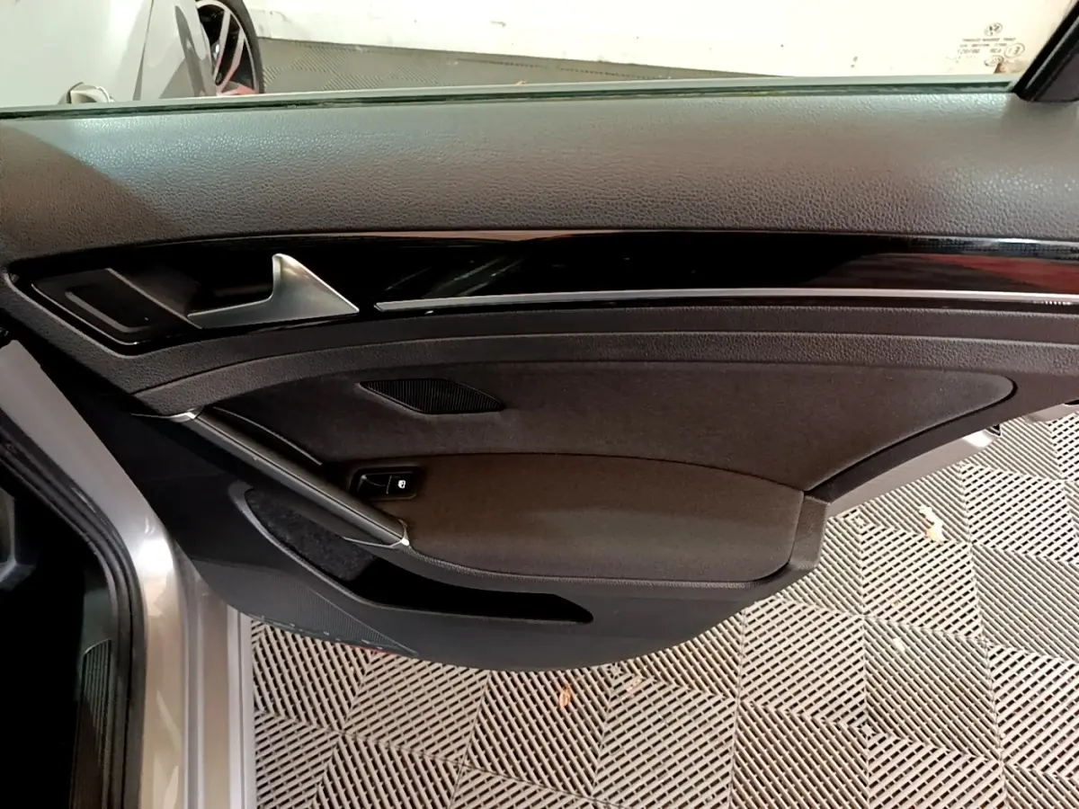 Porte côté gauche ouverte d'une Volkswagen Golf gris clair, montrant le panneau intérieur noir avec poignée argentée.