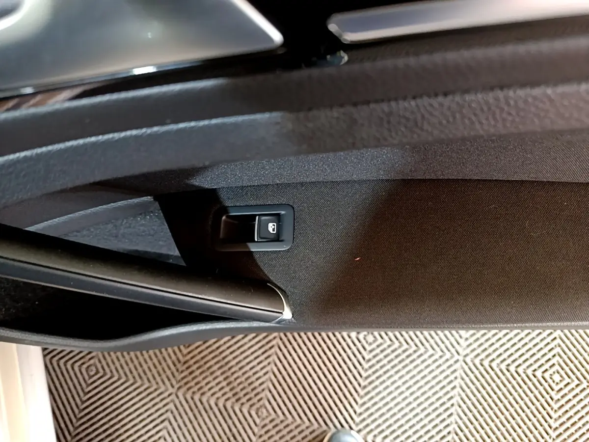 Bouton de verrouillage de porte sur la garniture intérieure côté conducteur d'une Volkswagen Golf gris clair, vue rapprochée.