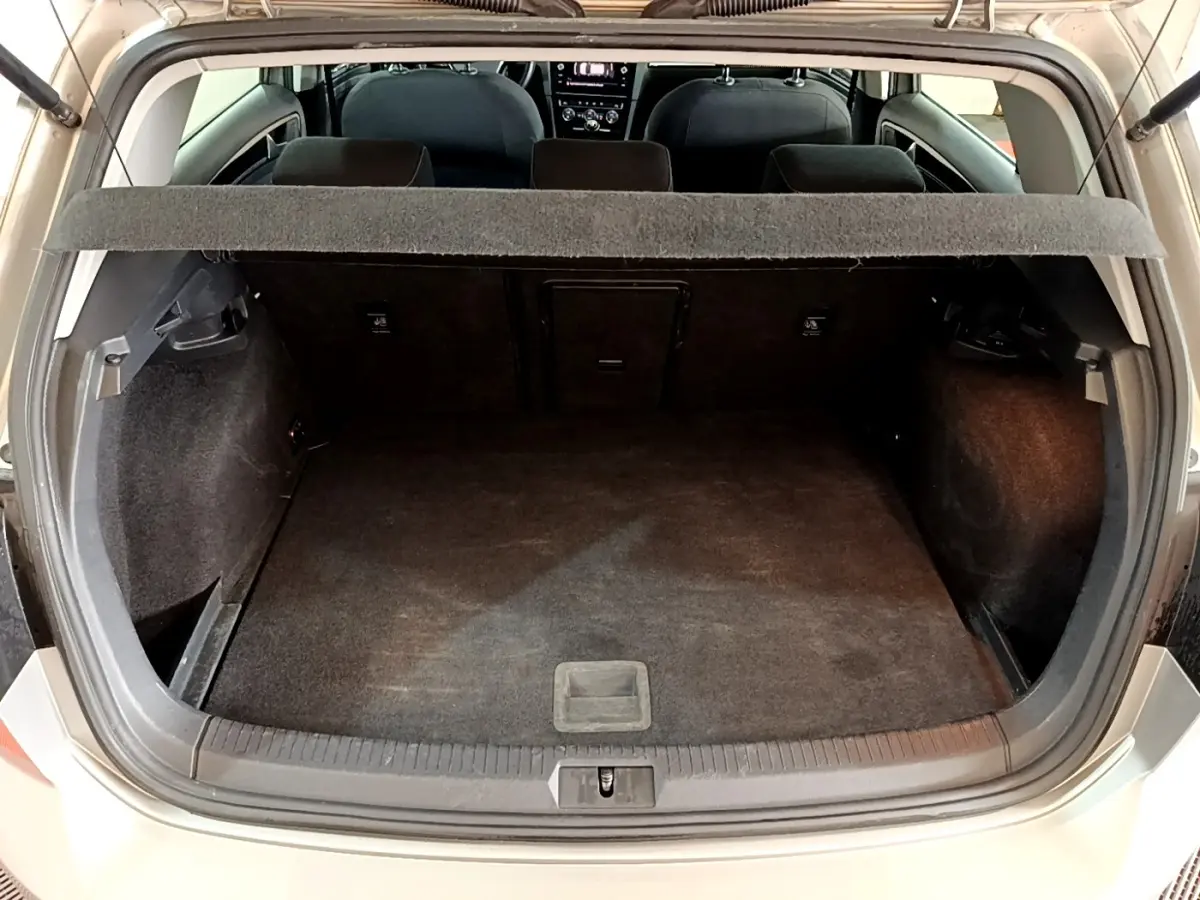 Vue arrière du coffre ouvert d'une Volkswagen Golf gris clair, montrant l'espace de chargement et la banquette arrière.