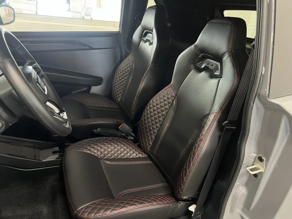 Vue intérieure côté conducteur de la LIGIER JS50 0.5 REVO D+ ULTIMATE avec sièges noirs à surpiqûres rouges.