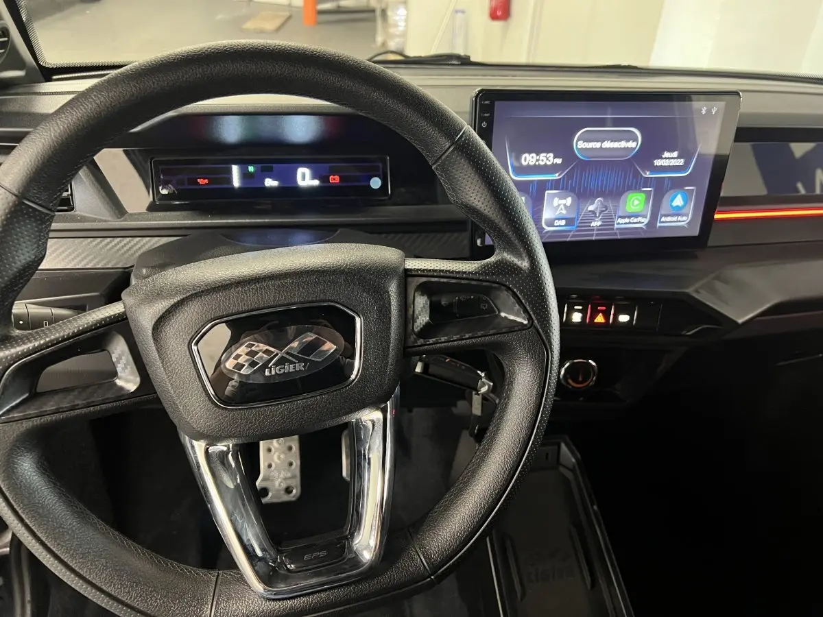 Vue intérieure centrée sur le volant noir et le tableau de bord digital du Ligier JS50 bleu 2026.