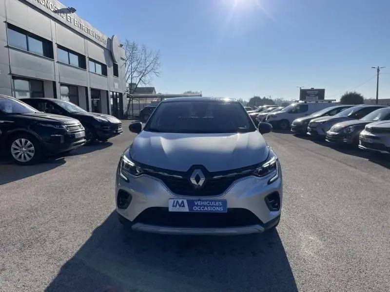 Vue frontale d'un Renault Captur gris métal 2022, version hybride 1.6 E Tech Intense, sur un parking extérieur.