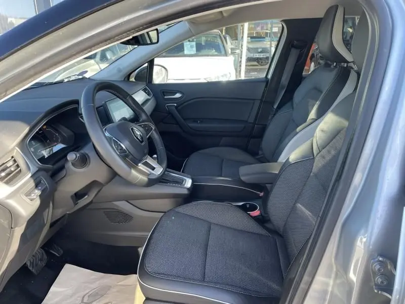 Intérieur avant côté conducteur d'un Renault Captur gris métal 2022, sièges tissu noir et tableau de bord moderne.